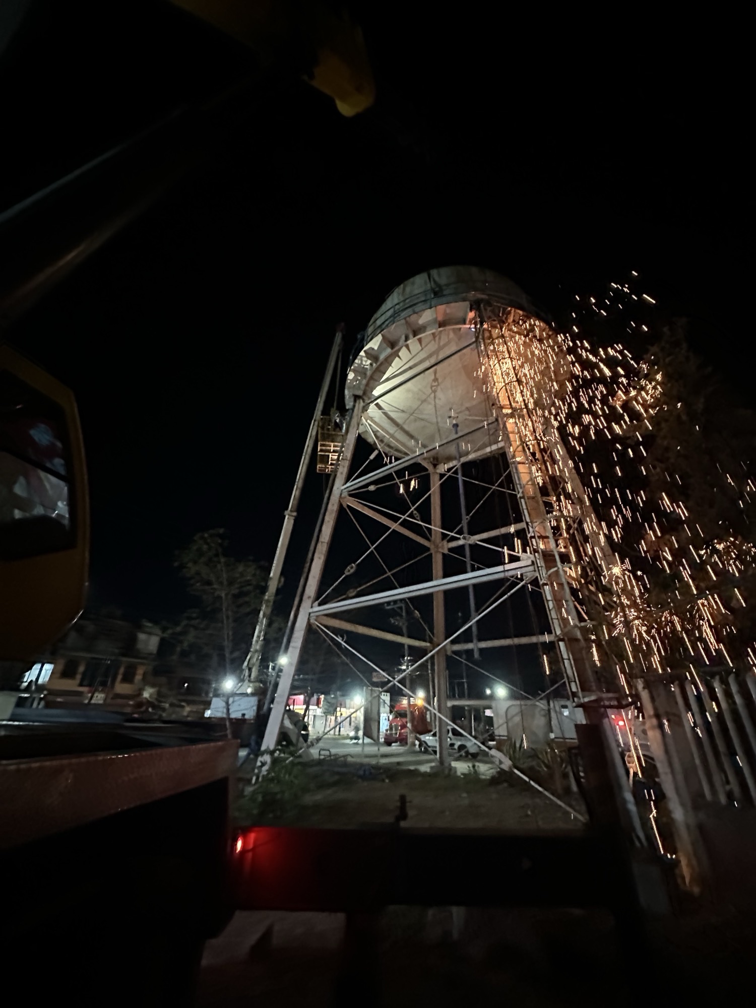 Corte en altura de un tanque elevado con lluvia de chispas durante una maniobra nocturna de desmantelamiento